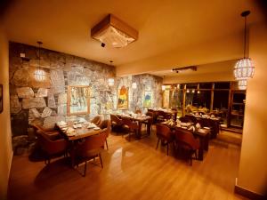 a restaurant with tables and chairs and a stone wall at Diwan-e-Hunza Resort in Gulmit
