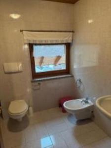a bathroom with a toilet and a sink and a window at Appartamenti Famiglia Rizzi in Campitello di Fassa +5 photos