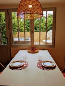 a dining table with two glasses and a chandelier at La Rue Perdue - Gîte & Spa in La Réole