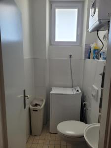 a white bathroom with a toilet and a window at Mary in Zadar