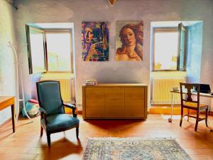a living room with a desk and a chair and paintings at La Casa del Voltone in Pontremoli