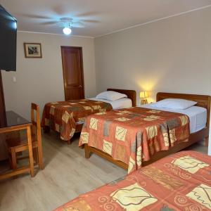 a hotel room with three beds and a flat screen tv at Hotel La Molina in Lima