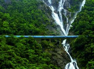 a train traveling over a bridge over a waterfall at Villa Retreat Cottages Ramnagar in Londa