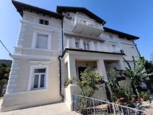 a white house with a balcony on top of it at Apartman Beti in Opatija
