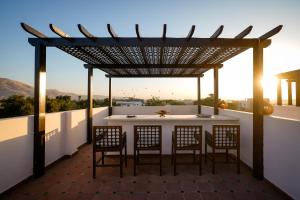 a patio with a table and chairs under a pergola at Al Wadi Hôtel in Al Aqālitah