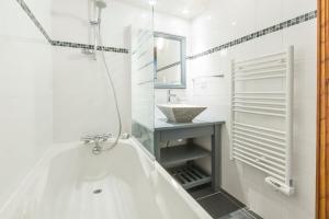 a white bathroom with a tub and a sink at Les Aiguilles de Warens - Combloux in Combloux