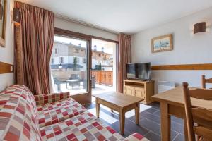 a room with a bed and a television and a table at Les Aiguilles de Warens - Combloux in Combloux