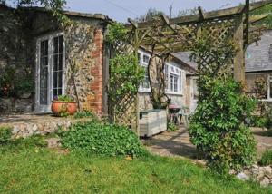 ein Backsteinhaus mit einer Pergola im Hof in der Unterkunft Yarde cottage rural Devon Dog friendly in Membury