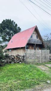 a wooden barn with a red roof and a fence at Chalé Xodó da Serra Urubici in Urubici