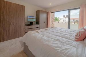 a bedroom with a large bed and a large window at Condo Verde Oasis - Central 2 bedroom with pool, gym, private terrace - At Veranto Condos in Playa del Carmen