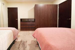 a bedroom with two beds and a entertainment center at Condo Verde Oasis - Central 2 bedroom with pool, gym, private terrace - At Veranto Condos in Playa del Carmen