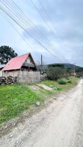 a barn with a red roof next to a dirt road at Chalé Xodó da Serra Urubici in Urubici +18 photos