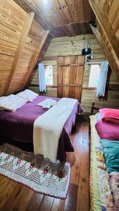 a bedroom with two beds in a log cabin at Chalé Xodó da Serra Urubici in Urubici