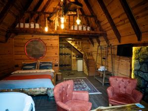 a bedroom in a log cabin with a bed and chairs at Sisorti bungalow otel in Çamlıhemşin