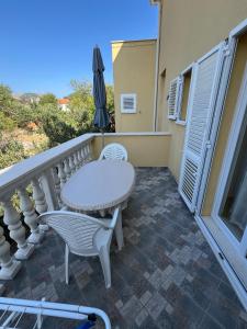 a balcony with a table and chairs and an umbrella at Sunce economy room with kitchenette in Grebaštica +2 photos