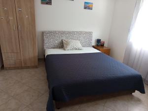 a bedroom with a large bed with a blue blanket at Mica apartmani in Sutomore
