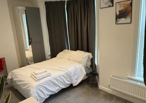 una camera da letto con un letto bianco con asciugamani sopra di Peeams Abode Erith a Erith