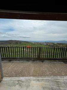 a wooden bench with a view of a field at Albergue de peregrino Cruz de Fierro in Foncebadón