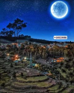 a full moon rising over a city at night at The Wooden Homestay in Almora +8 photos