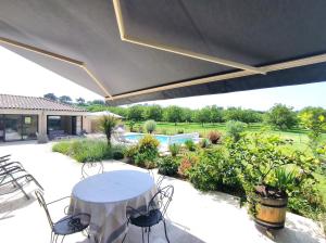a patio with a table and chairs and a pool at Villa Poujol en Dordogne, piscine chauffée in Saint-Crépin-et-Carlucet