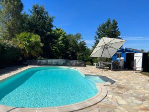 a swimming pool with a table and an umbrella at Les Acacias in La Milesse