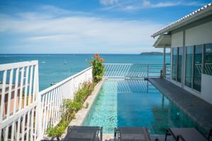 a swimming pool on the side of a house overlooking the ocean at mona seaview pool villa beach front AoYon Beach in Ban Ao Makham