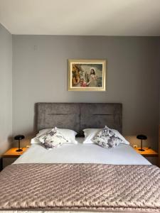 a bed with two pillows and a picture on the wall at Apartments Villa Dinka in Hvar