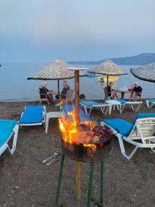 een barbecue op het strand met mensen die onder parasols zitten bij H A Pansiyon in Ayvacık