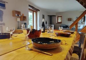 a wooden table with wine glasses and a bowl on it at Marmite et traversin in Cénevières