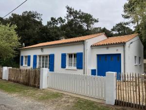 ein Haus mit blauen Türen und einem weißen Zaun in der Unterkunft Maison 100 m2 plein pied pour 6 personnes 300 m de la plage in Chaucre