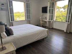 a bedroom with a bed and two windows and a desk at Hôtel Beau Site - Cap d'Antibes in Antibes