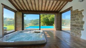 a hot tub in a room with large windows at Agriturismo Elisei in Gualdo di Macerata