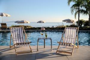 two chairs and a table next to a pool at Hôtel La Villa Douce in Rayol-Canadel-sur-Mer
