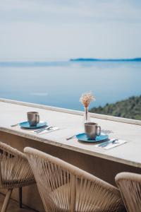 a table with two cups and a vase of flowers at Hôtel La Villa Douce in Rayol-Canadel-sur-Mer