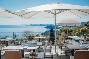a restaurant with tables and chairs and an umbrella at Hôtel La Villa Douce in Rayol-Canadel-sur-Mer