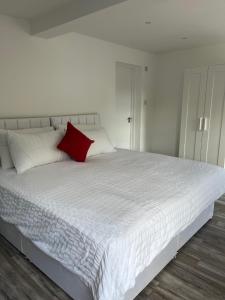 ein weißes Bett mit einem roten Kissen darauf in der Unterkunft Yugogo One-Bedroom Apartment 37 London Road in St Albans