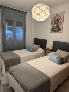 sypialnia z 2 łóżkami i żyrandolem w obiekcie Apartamento la almadraba w mieście Chiclana de la Frontera +21 zdjęć