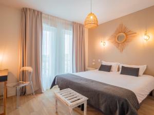 ein Hotelzimmer mit einem großen Bett und einem Spiegel in der Unterkunft Hotel La Licorne in Carnac