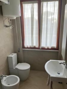 a bathroom with a white toilet and a sink at Casa Primavera in Cinquale