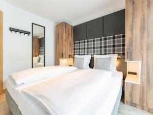 een slaapkamer met een groot wit bed en een spiegel bij Tauernlodge Eben A3 in Eben im Pongau