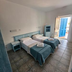 two beds in a room with two tables and a window at Vel Marì - Rooms on the Beach in Alghero
