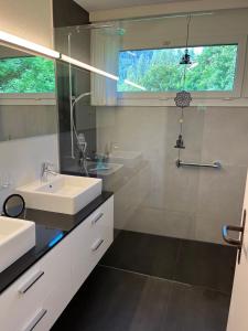Un baño con dos lavabos y una ducha. en Tulai D74, en Scuol