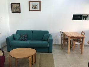 a living room with a blue couch and a table at Gîte dans un petit village pyrénéen in Lézignan