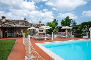 a house with a swimming pool and a patio with umbrellas at Resort Tenuta La Rotta - Rooms & Pool in Ravenna
