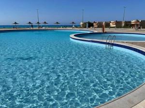 a large swimming pool with blue water and umbrellas at North coast ,El sahel in Dawwār ‘Abd Allāh