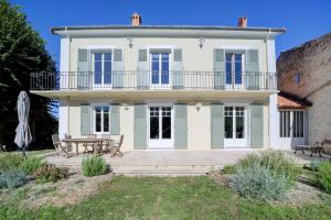 a large white house with blue windows and a patio at Le Nid d'Estoublon in Estoublon
