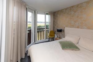 a bedroom with a white bed and a balcony at Appartement Lac marin in Vieux-Boucau-les-Bains
