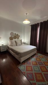 a bedroom with a large bed and a rug at Blue haven guest house in Caniço