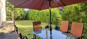 a table and chairs with an umbrella in a yard at Bea Apartman in Balatonfüred