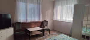 a room with a table and a chair and a television at Bea Apartman in Balatonfüred